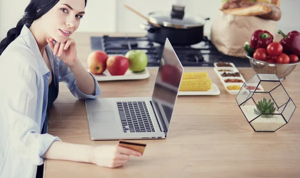 Donna sorridente shopping online con computer e carta di credito in cucina — Foto Stock