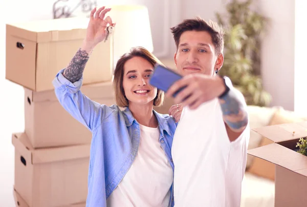 Mladý manželský pár dělat selfie držení klíče v novém bytě — Stock fotografie
