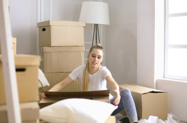 Güzel bekar bir kadın kutuları açıyor ve yeni bir eve taşınıyor. Bir kadın buraya bak tablet