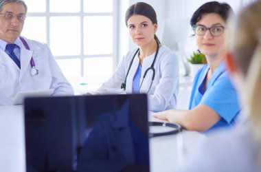 Ciddi bir tıbbi ekip hastaları parlak bir ofiste tartışıyor.