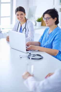 Ciddi bir tıbbi ekip hastaları parlak bir ofiste tartışıyor.