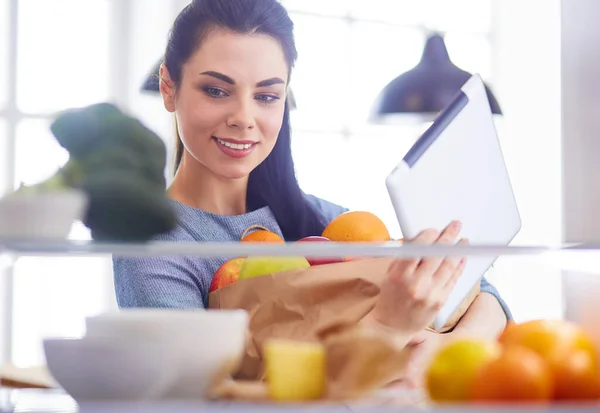 Mulher sorridente tirando uma fruta fresca da geladeira, conceito de comida saudável — Fotografia de Stock
