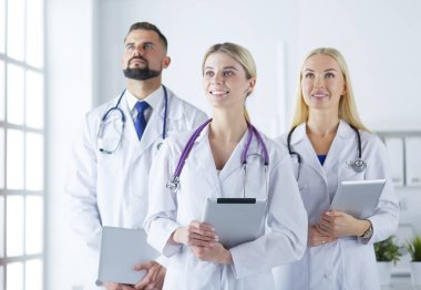 Gülümseyen doktorlar çalışırken bir arada duruyorlar.