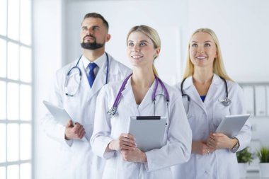 Gülümseyen doktorlar çalışırken bir arada duruyorlar.