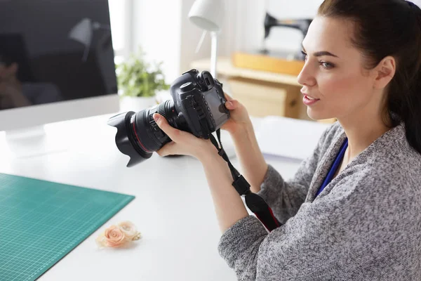 Jonge vrouw ontwerper staat in de buurt van de werkplek en fotograferen op digitale camera — Stockfoto