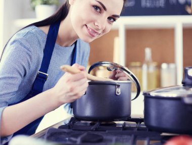 Mutfakta ahşap kaşıkla yemek pişiren kadın