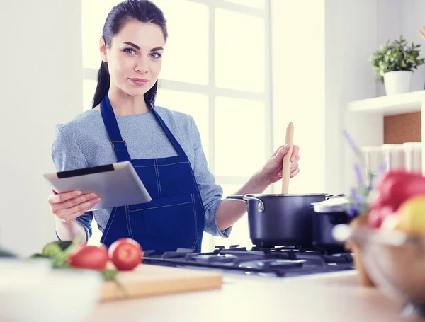 Junge Frau kocht mit Tablet-Computer in ihrer Küche — Stockfoto