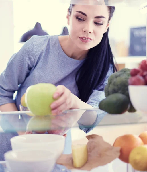 Uśmiechnięta kobieta wyciągająca świeże owoce z lodówki, koncepcja zdrowej żywności — Zdjęcie stockowe