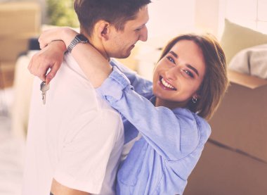 Mutlu genç çift yeni evlerinin anahtarlarını gösteriyor.