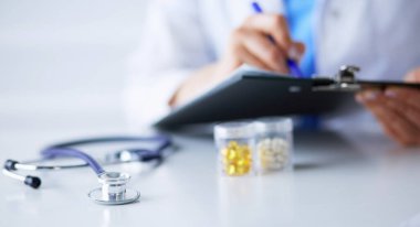 Kadınların elleri bir kağıt parçasına yazı yazıp masasında kalem bırakırlar.