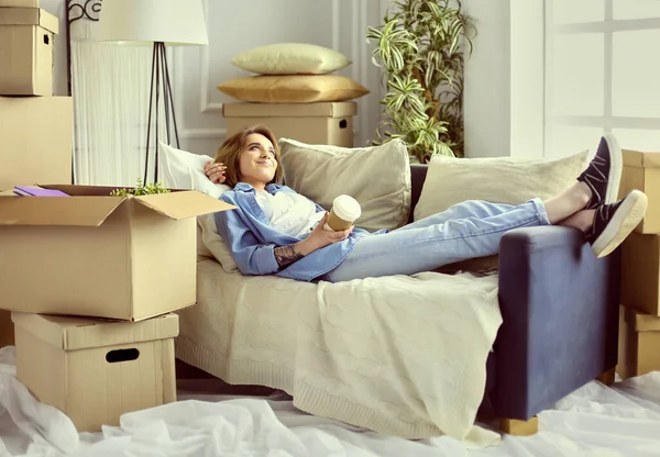 Uśmiechnięta młoda kobieta leżąca na kanapie w nowym mieszkaniu — Zdjęcie stockowe