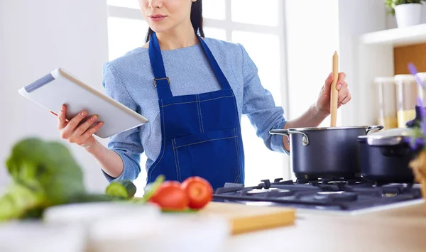 Junge Frau kocht mit Tablet-Computer in ihrer Küche — Stockfoto