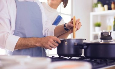 Evdeki mutfakta birlikte yemek pişiren çift.