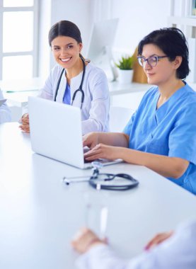 Ciddi bir tıbbi ekip hastaları parlak bir ofiste tartışıyor.