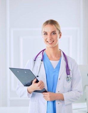 Kadın doktor hastanede dosyayla bekliyor.