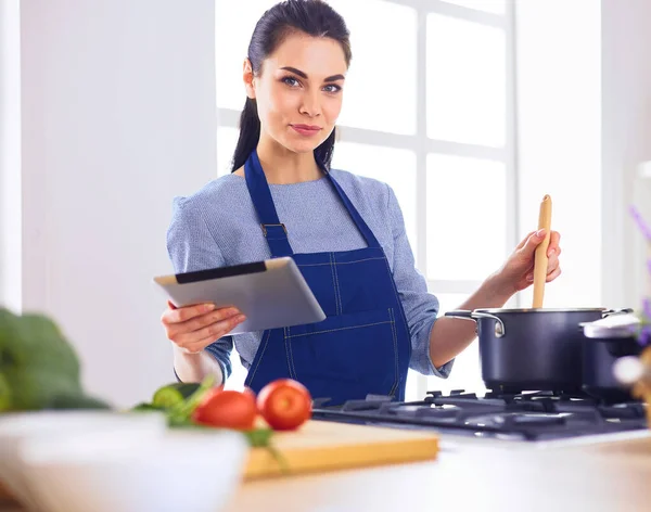 Giovane donna che utilizza un tablet per cucinare nella sua cucina — Foto Stock