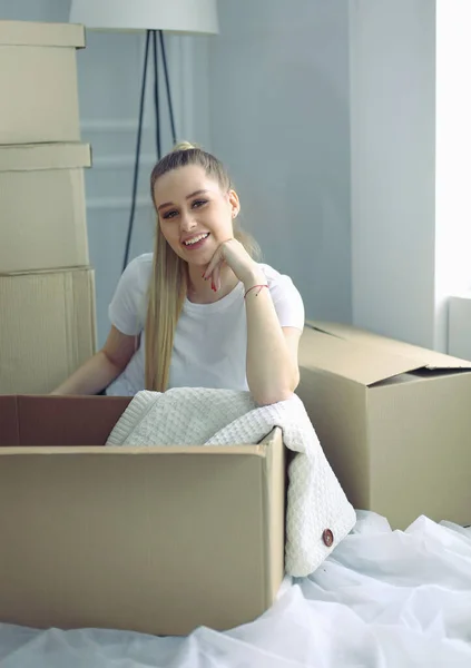 A beautiful single young woman unpacking boxes and moving into a new home — Stock Photo, Image