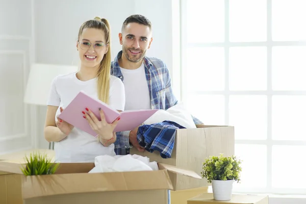 Ein frisch verheiratetes Paar packt Kartons aus und bezieht ein neues Zuhause. Positive Emotionen. — Stockfoto