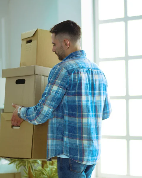 A moving man sitting on the floor in empty apartment, Among the Boxes, Checking the List of Things