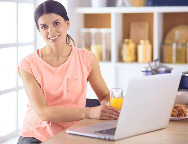 Молода жінка на кухні з портативним комп'ютером шукає рецепти, посміхається. концепція продовольчого блогера — стокове фото