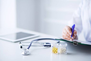 Kadınların elleri bir kağıt parçasına yazı yazıp masasında kalem bırakırlar.