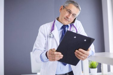 Erkek doktor hastanedeki panoya notlar yazıyor.