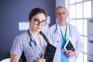 Bir doktor ekibi, kadın ve erkek, ofiste bekliyorlar.