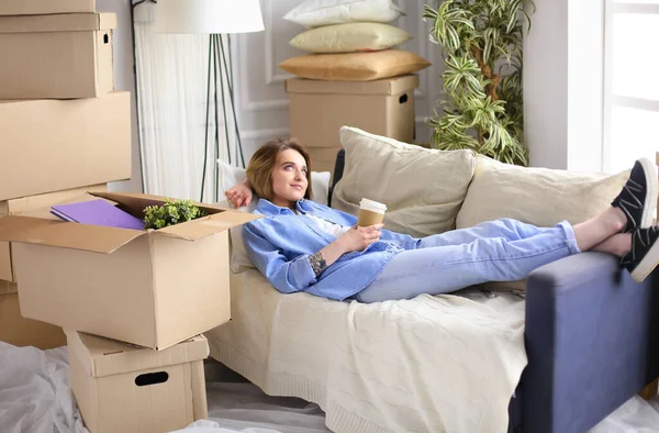 若いです女性の移動ボックスの上に横たわるソファで新しい家 — ストック写真
