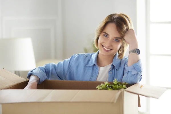 Egy gyönyörű, egyedülálló fiatal nő dobozokat pakol ki és új otthonba költözik. — Stock Fotó