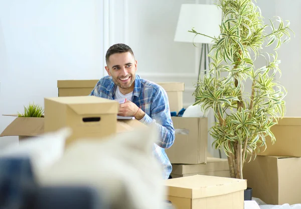 A moving man sitting on the floor in empty apartment, Among the Boxes, Checking the List of Things