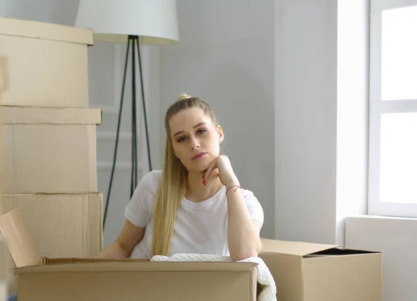 Krásná svobodná mladá žena vybaluje krabice a stěhuje se do nového domova — Stock fotografie