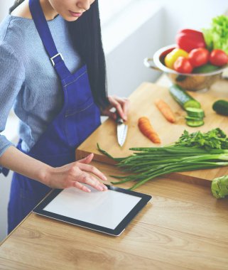 Mutfakta sebze doğrayan genç bir kadın.