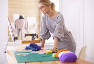 Moda tasarımcısı kadın stüdyoda tasarımları üzerinde çalışıyor.