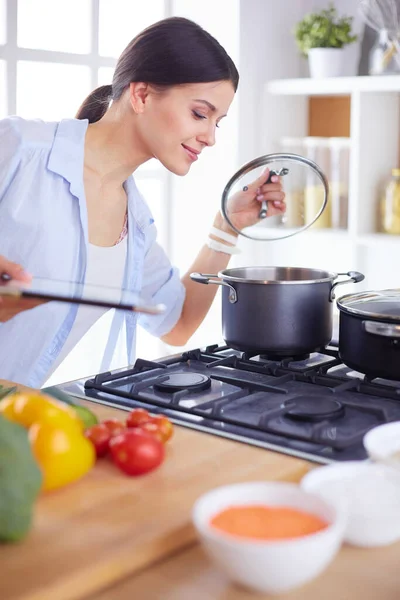 Giovane donna in piedi vicino al fornello in cucina — Foto Stock