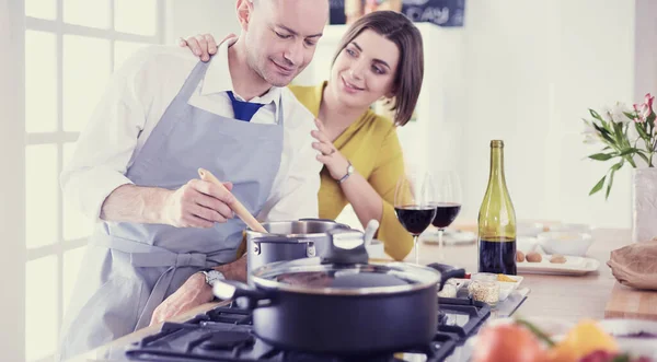 Attractive couple in love cooking and opens the wine in the kitchen while they cook dinner for a romantic evening — Stock Photo, Image