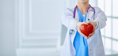 Stetoskoplu kadın doktor kollarında kalp tutuyor. Tıpta sağlık ve kardiyoloji kavramı