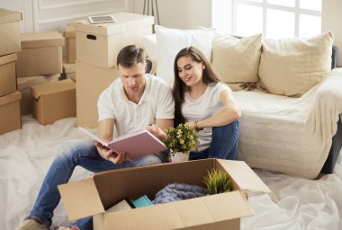 Yeni evlerinde karton kutuları açan sevimli bir çift.