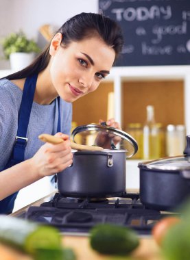 Mutfakta ahşap kaşıkla yemek pişiren kadın