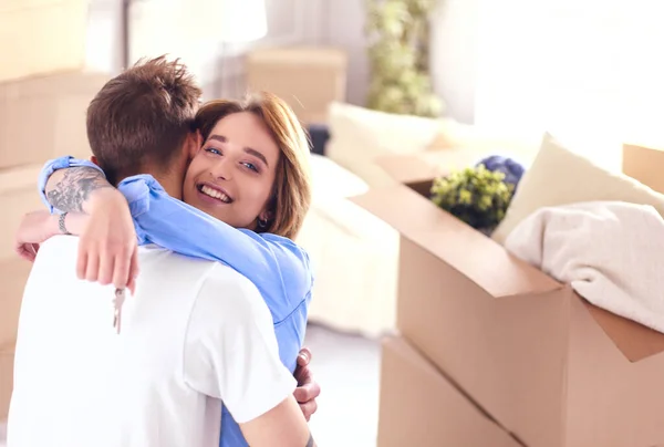 Jovem casal feliz abraçando, mostrando as chaves para a nova casa — Fotografia de Stock