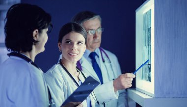 Bir grup doktor bir klinikte röntgenleri inceliyor, teşhis koymayı düşünüyorlar.
