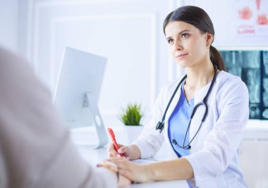 Kadın doktor hastane danışma odasında bir hastayı sakinleştiriyor, elini tutuyor.