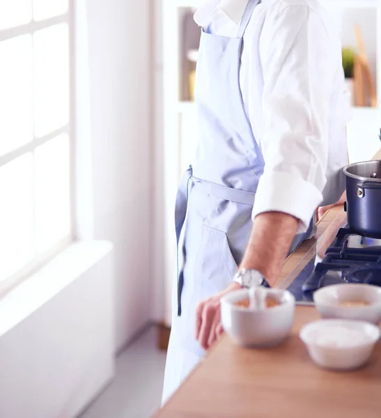 Pohledný muž vaří v kuchyni a usmívá se — Stock fotografie