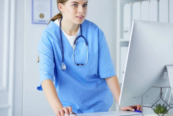 Портрет женщины-врача, заполняющей медицинскую форму, стоя возле стойки регистрации в клинике или больнице скорой помощи — стоковое фото