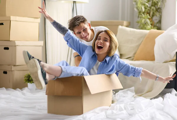 Šťastný pár baví a na koni v kartonových krabicích v novém domově — Stock fotografie