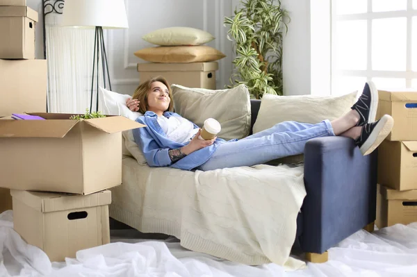 Sorridente giovane donna sdraiata sul divano in un nuovo appartamento — Foto Stock