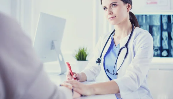 Female doctor calming down a patient at a hospital consulting room, holding her hand — Stock Photo, Image