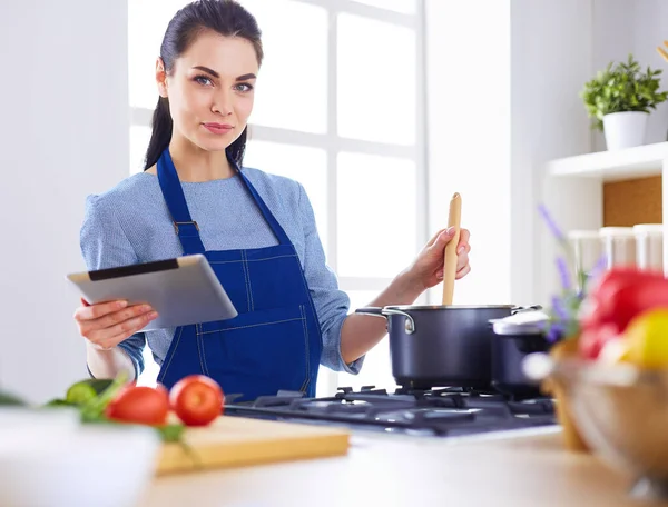 Νεαρή γυναίκα που χρησιμοποιεί υπολογιστή tablet για να μαγειρέψει στην κουζίνα της — Φωτογραφία Αρχείου