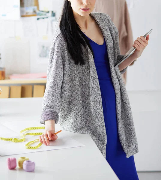 Schöne junge Frau arbeitet am digitalen Tablet und lächelt, während sie an ihrem Arbeitsplatz sitzt — Stockfoto