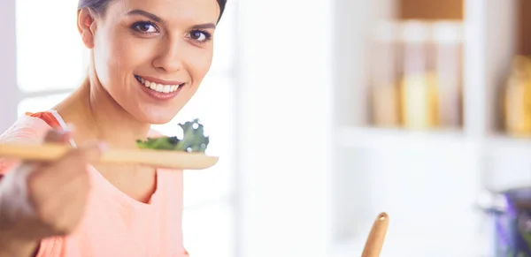 Улыбающаяся молодая женщина смешивает свежий салат на кухне. — стоковое фото