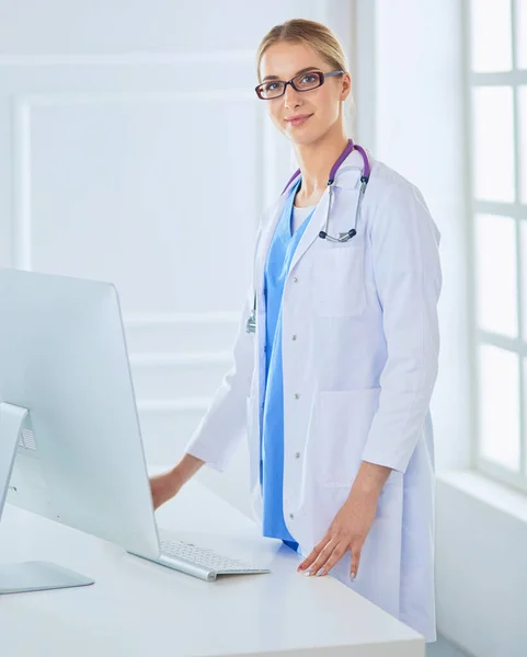 Young doctor woman standing near table, isolated on white background — Stock Photo, Image